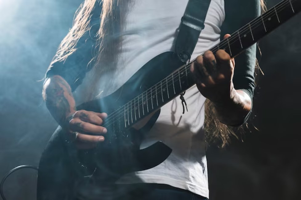 a tattoed guitar player playing guitar with smoke floating around