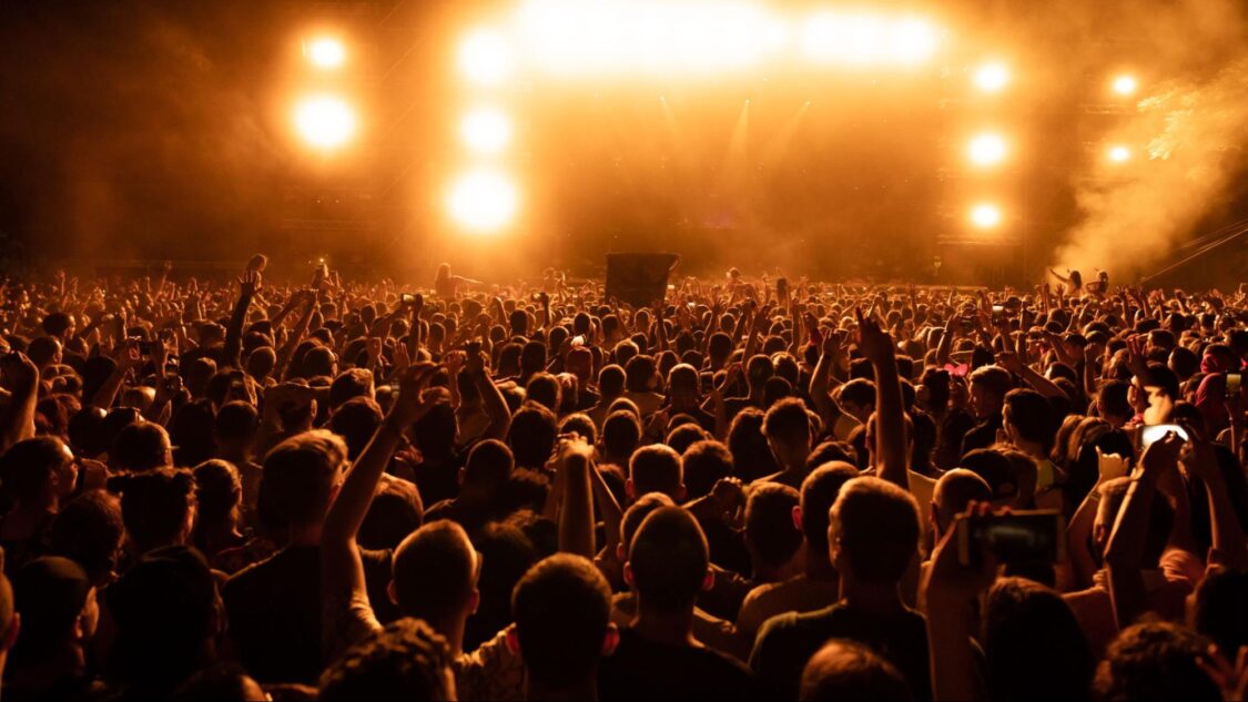 excited audience watching confetti fireworks and having fun at a music festival at night