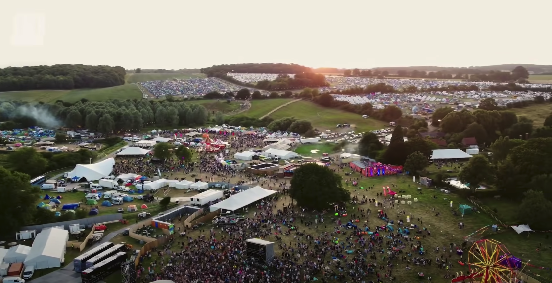 Top view photo of a large music festival with crowds of people and various booths