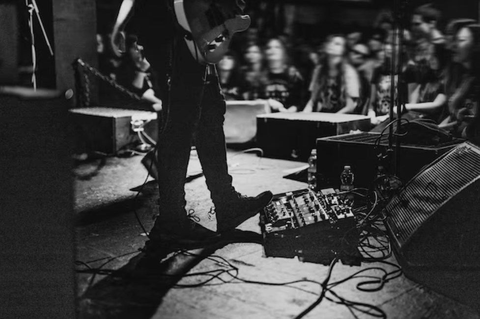 a guitar player using a pedal board on stage during a live concert