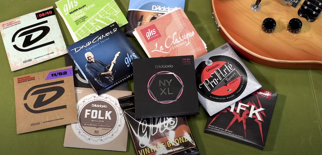 Photo showing different brands of guitar strings, with a partial view of a guitar visible in the frame