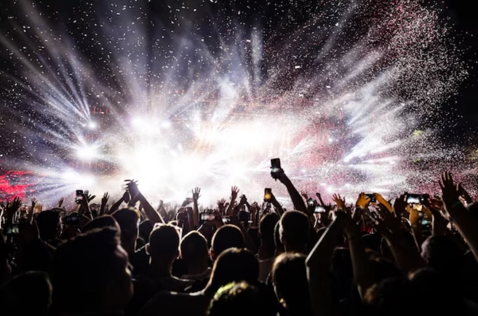 excited audience watching confetti fireworks and having fun at a music festival at night